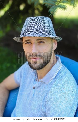 Young Man Sitting In Bag Chair Outside And Wearing Blue Hat. Concept Of Vacations And Resting In Ope