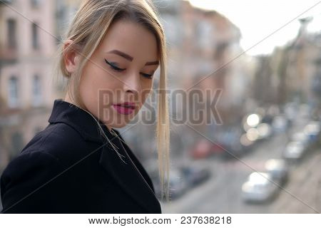 Portrait Of A Young Woman In A Black Suit Close-up Against A Background Of A Blurry City In The Rays
