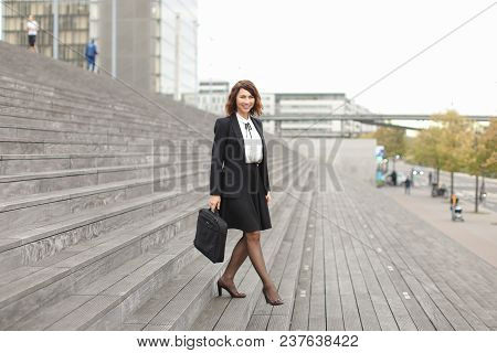 Beautiful Businesswoman Going Down On Stairs In High Buildings Background. Concept Of Career And Bus
