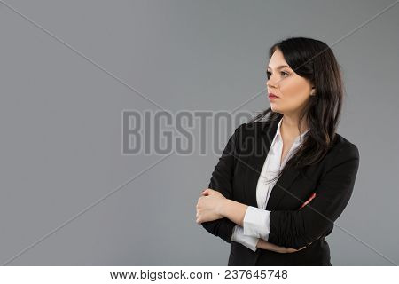 Standing Businesswoman Portrait On Light Grey Background. Copy Space At Left
