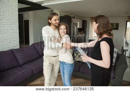 Smiling Young Couple Handshaking Real Estate Agent Buying Or Renting New Home, Satisfied Customers R