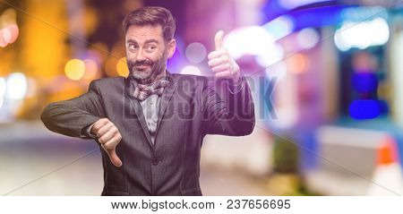 Middle age man, with beard and bow tie confused with thumbs up and down, trying to take a decision expressing doubt and frustration at night club