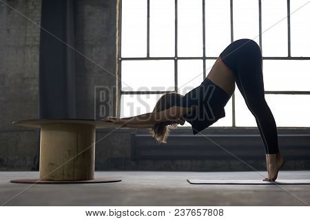 Cute Girl In A Black Sportswear Engaged In Yoga On The Window Background In A Loft Style Hall. She S