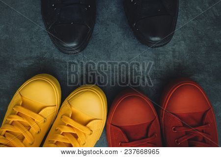 Youth Confrontation Conceptual Image. Young People In Colorful Sneakers Confronting A Person In Blac