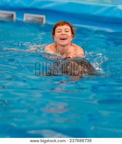 Young Happy Girl Swimming With Dolphin
