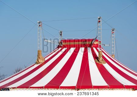 Roof Of A Circus Tent With Red And White Stripes And Four Masts Against A Blue Sky
