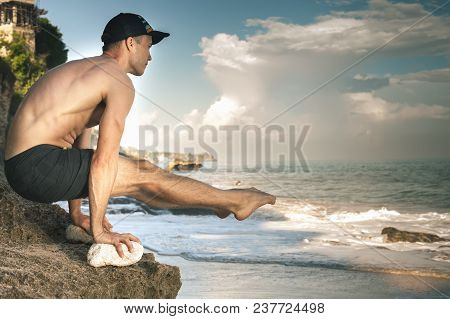 Handsome Man Doing Yoga Near The Beach With Blue Sky And Sea Background. Relaxing And Healthy Lifest