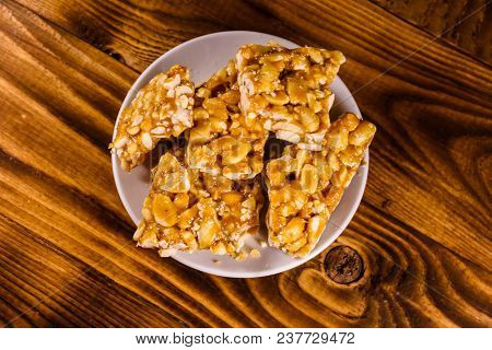 Ceramic Plate With Peanut Brittles On Rustic Wooden Table. Top View