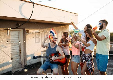 Group Of People Holding National Flags And Having Fun On Rooftop