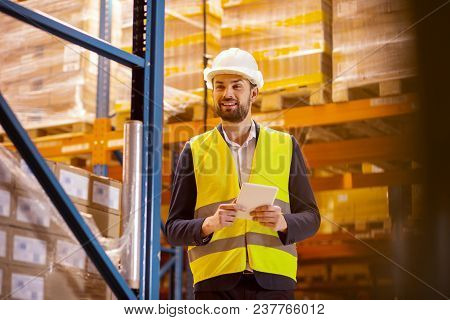 Inventory Control. Joyful Positive Man Holding A Tablet While Doing The Revision Of The Inventory