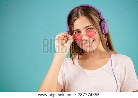 Close Up Photo Of Glamour Woman With Pinck Sunglasses And Blue Headphones Is Posing To The Camera