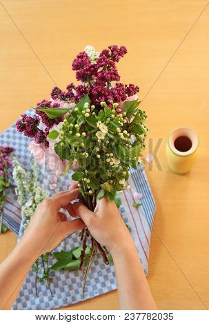 Hands Of A Young Woman Arranging Flowers On A Wooden Table, For A Vase