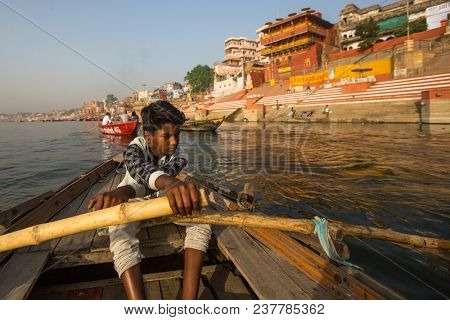 VARANASI, INDIA - MAR 26, 2018: Boatmen on a boat glides through water on Ganges river along shore of Varanasi. According to legends, the city was founded by God Shiva about 5000 years ago.
