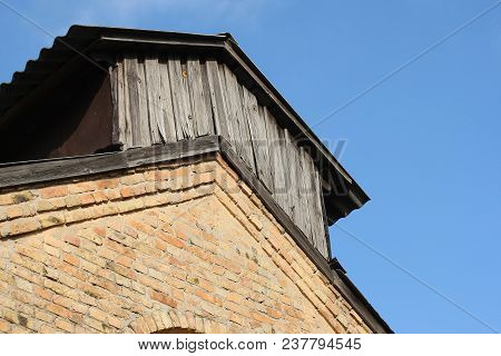 Wooden Extension On An Old Brick Building. Against The Blue Sky
