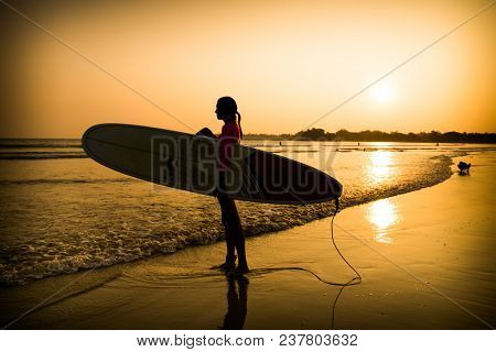 Beautiful surfer on sunset at  Weligama beach in Sri Lanka.