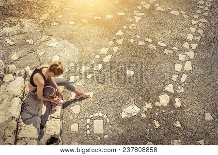Women runner bootlace on her boot after running in sunny day under sunlight from blue sky on the stone steps.