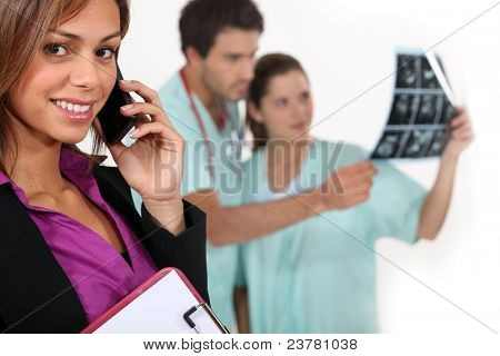 Direttore ospedale su un telefono come medici sguardo a raggi x in background