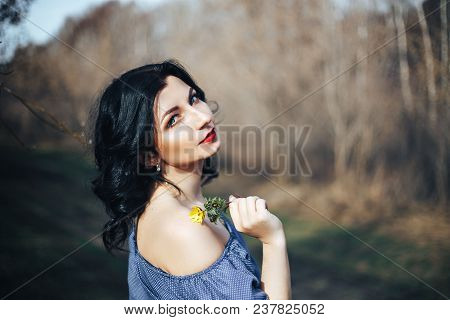 Beautiful Girl In Blue Dress Standing Near Spring Garden Against A Background Of Green Grass And Gra
