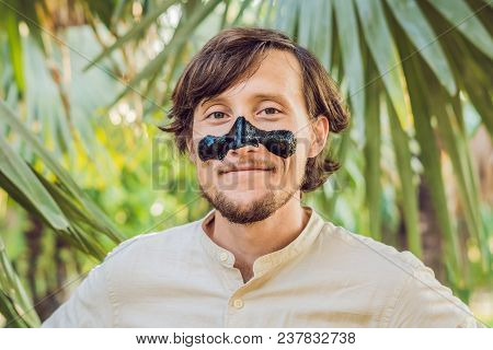 Happy Man With Black Mask On The Face. Photo Man Receiving Spa Treatments. Beauty Skin Care Concept.