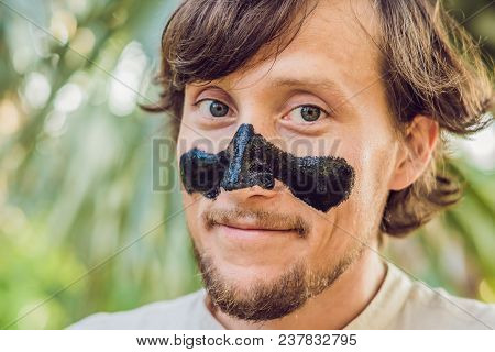 Happy Man With Black Mask On The Face. Photo Man Receiving Spa Treatments. Beauty Skin Care Concept.