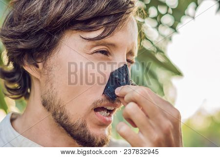 Happy Man With Black Mask On The Face. Photo Man Receiving Spa Treatments. Beauty Skin Care Concept.