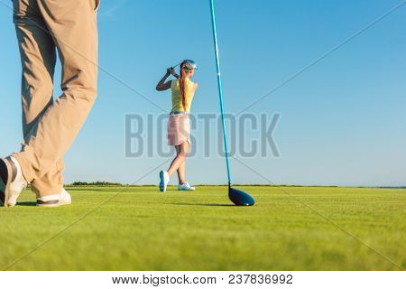 Low-angle full length view of a female professional golfer hitting a long shot, during a challenging matchplay game for two players outdoors in a sunny day