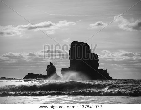 Sea Stack Sharp Silhouette By Sunset Sky. Evening Light On The Rocks, Boulders And Cliff Face Of Tal