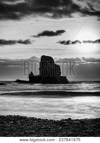 Sharp Silhouette Of A Cliff Against The Background Of Sunset. Sea Waves Break On The Rocks. Talisker