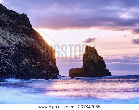 Sea Stack Sharp Silhouette By Sunset Sky. Evening Light On The Rocks, Boulders And Cliff Face Of Tal