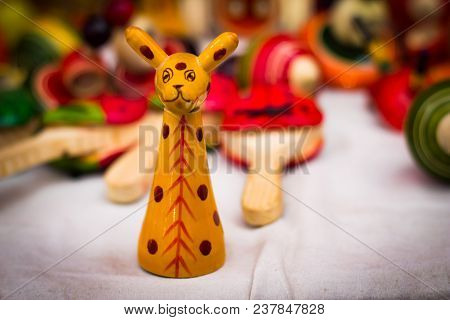 A Yellow Wooden Giraffe Figure Vintage Channapatna Toy Against A Blurred Background