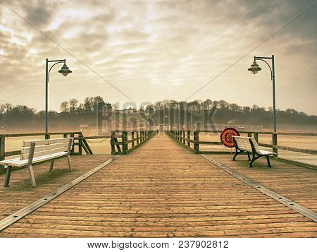 Old Wood Beach Bridge In Goehren With Nobody. Autumnal Misty Weather With Cloudy Sky.
