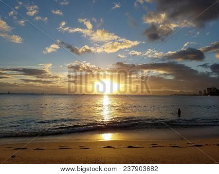 Dramatic Lighting As Sunsets Over The Ocean With Waianae Mountains In The Distance With Light Reflec