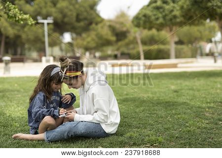 Sisters Looking At A Mobile Phone In A Park.