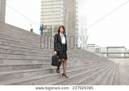 Caucasian Businesswoman Going Down On Stairs In High Buildings Background. Concept Of Career And Bus