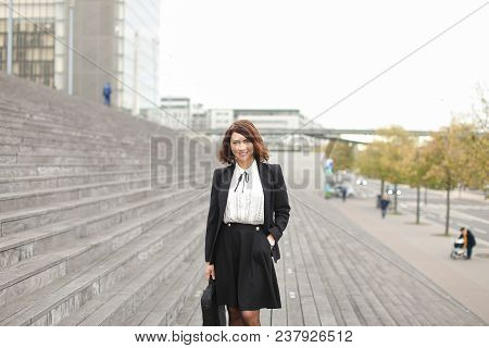Secretary Standing On Stairs With Bag And High Buildings In Background. Concept Of Profession And Bu