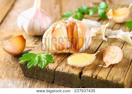 Heads Of Garlic With Parsley On A Wooden Table