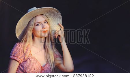 Beautiful Young Woman In Pink Dotted Summer Dress And Sun Hat Points To Copy Space, Looking At Camer