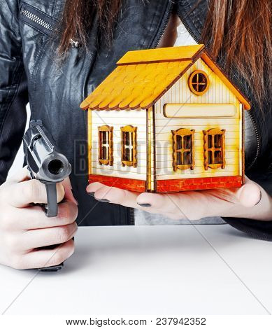 Armed Woman With A Gun In His Hand And A Toy House Under His Arm. The Right Of Armed Protection Of P