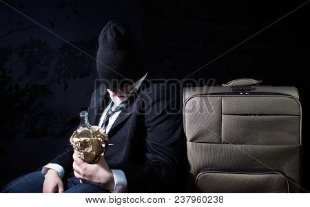 Photo Of A Drunk Homeless Business Man Sitting With Empty Bottle And Travel Suitcase.