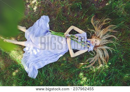Attractive Young Girl With Blonde Dren Hair And Natural Make-up Smelling Blue Purple Iris Flowers Ly