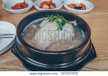 Close Up View Of Bowl Of Hot Samgyetang And Kimchi Side Dishes On Background