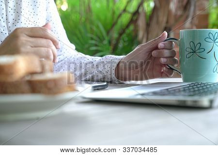 Working On The Computer And Cell Phone While Having Breakfast. Work From Home Or Flexi Time Concept.