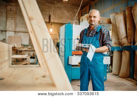 Carpenter with notebook, wood processing, factory