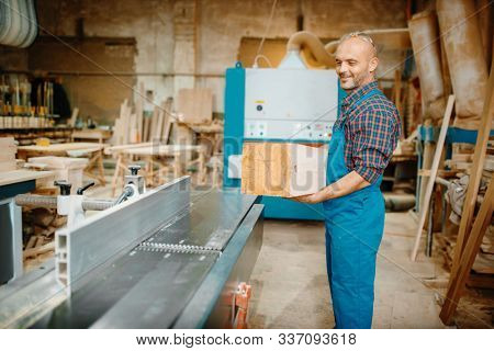 Carpenter processes wooden beam on plane machine