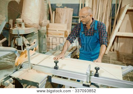 Carpenter cuts wooden board on circular saw