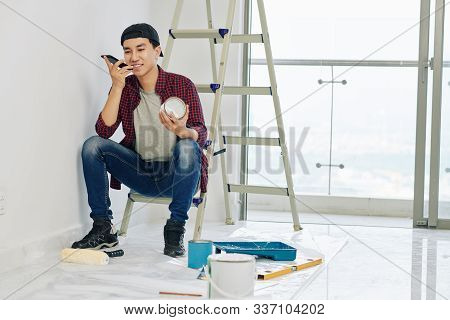 Smiling Young Man Recording Voice Message And Asking His Friends To Help Him With Painting Walls In 