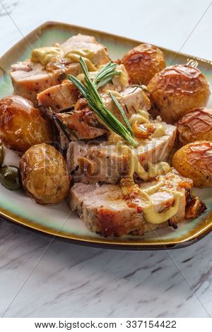 Sliced Honey Mustard Roast Pork Tenderloin With Baby Potatoes And Caperberry Garnish
