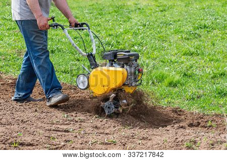 Cultivator For Tillage In The Garden,motor Cultivator. Man Farmer Plows The Land With A Cultivator.