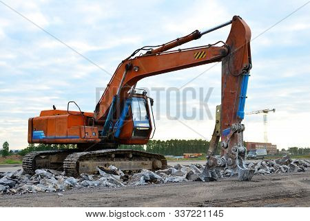 Excavator With Hydraulic Shears Breaks Asphalt On A Construction Site. Hydraulic Shear Crusher Pulve