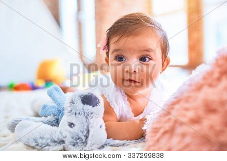 Beautiful infant happy at kindergarten around colorful toys lying on blacket